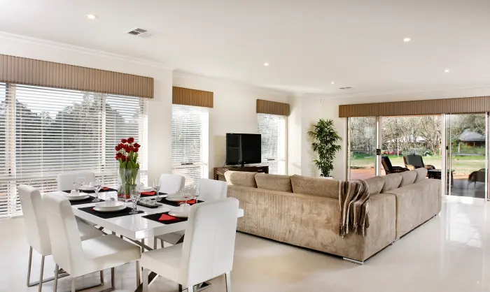 White-themed open dining and living room with brown sofa and window